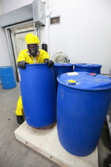 worker in uniform dealing with barrels of hazardous substance