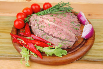 beef on wooden plate with peppers