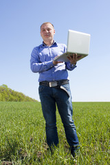 Businessmanon meadow, with a laptop