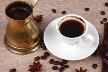 black Turkish coffee in small white mug with coffee beans