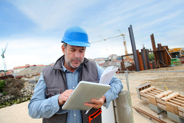 Construction manager controlling building site with plan