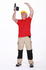 A mature handyman drilling the ceiling.