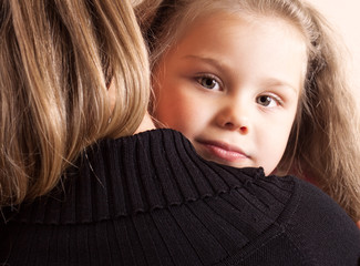 little girl looking over her shoulder of her mother