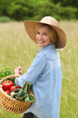 Woman in the countryside with vegetable basket.