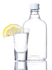 Bottle of vodka and wineglass with lemon isolated on white