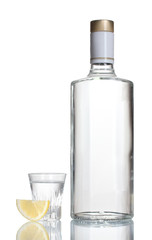 Bottle of vodka and wineglass with lemon isolated on white