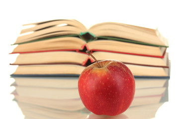 stack of open books with apple on white background close-up