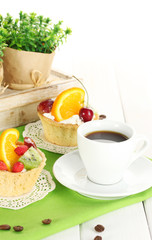 cup of coffee and sweet cakes with fruits on wooden table