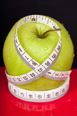green and wet apple with measure tape