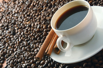 Cup of cappuccino with cinnamon and spilled out coffee beans.