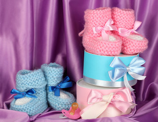 pink and blue baby boots, pacifier and gifts on silk