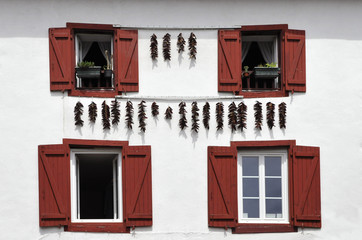 Red Spices hanging on a White Wall with Red Shutters