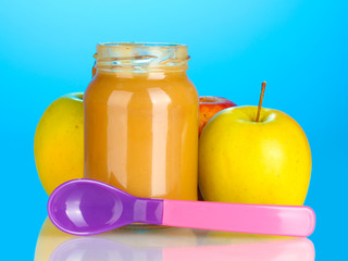 Jar with fruit baby food and spoon on colorful background