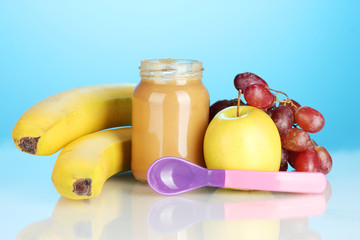 Jar with fruit baby food and spoon on colorful background