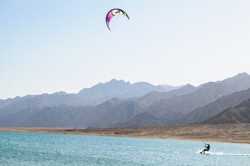 kitesurfer in lagoon surrounded by desert mountains