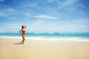 Fototapeta na wymiar Young beautiful wet woman sitting on the sand near ocean, Bali, 