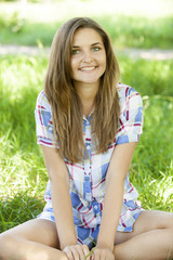 Beautiful teen girl in the park at green grass.