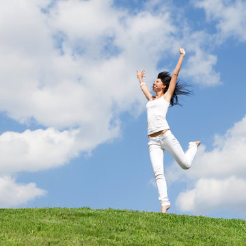 pretty young woman jumping on green grass
