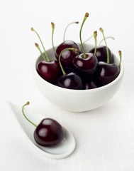 Cherry on white china spoon, cherries group in a white bowl