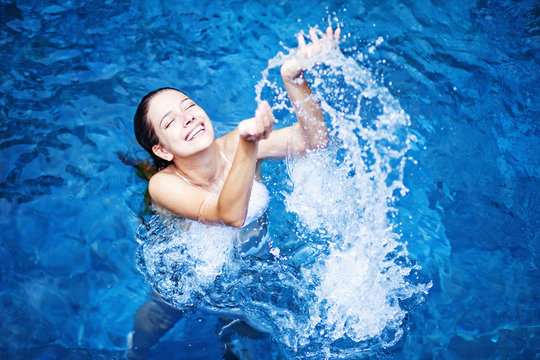 Young Beautiful Woman Splashing Water In Swimming Pool