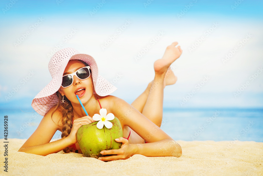 Fototapete Young woman in pink swimsuit with coconut cocktail on the beach,