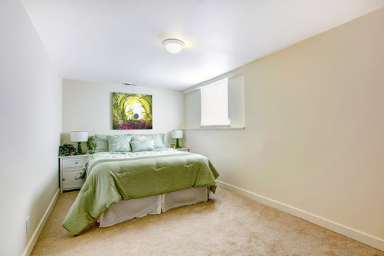 White large bedroom with green bed and art.