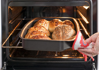 Baker's hand with bread in oven