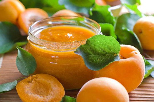 Apricot jam in jar and fresh fruits with leaves