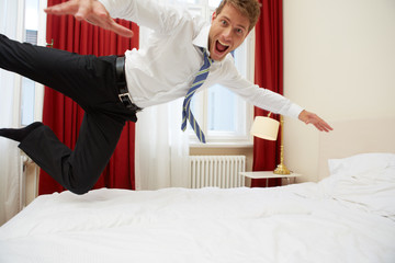 Junger Mann springt in Hotelbett