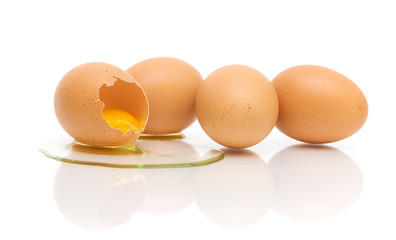 one broken and three whole eggs on a white background