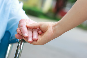 Senior women in wheelchair holding hands