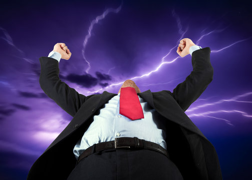 Businessman raising his arms to the stormy sky