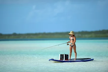 Acrylic prints Fishing Woman in bikini fishing and paddle boarding