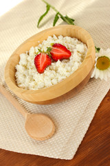 cottage cheese with strawberry in wooden bowl with wooden spoon