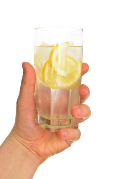Man's hand holding glass of water with ice and lemon