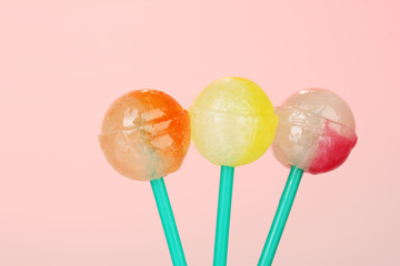 Bright and delicious lollipops on pink background close-up