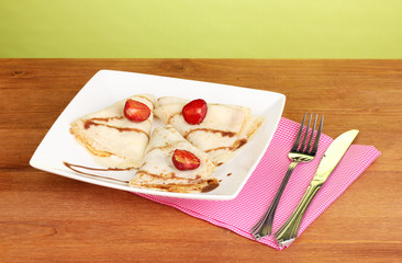 Stack of tasty pancakes on wooden table on green background