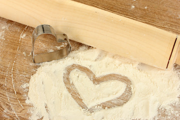 Cookie cutter with rolling pin on wooden table close-up