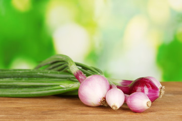 young onion on wooden table on bright green background close-up