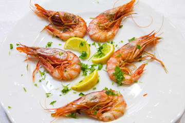 Shrimps with lemon slices and parsley on white plate
