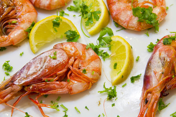 Shrimps with lemon slices and parsley on white plate