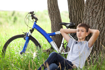 Fototapeta premium A teenager with a bicycle in the park on the grass