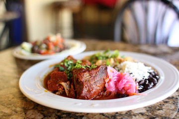 Cochinita pibil plate with pork served beans, and rice.