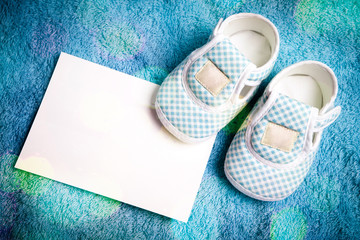Fototapeta na wymiar Baby shoes and empty postcard in vivid light style