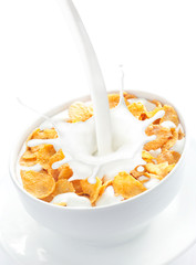 Milk pouring into a bowl of corn flakes