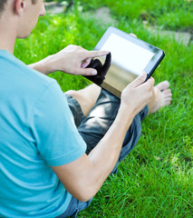 A young man uses tablet computer outdoor