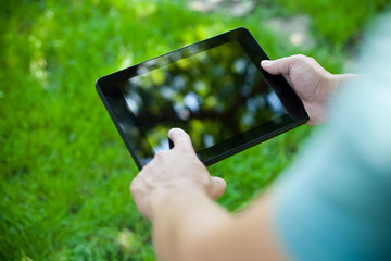 A young man uses tablet computer outdoor