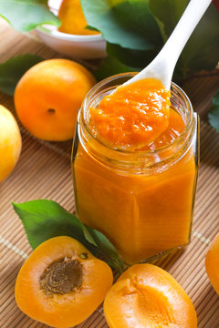 Apricot jam in jar and fresh fruits with leaves