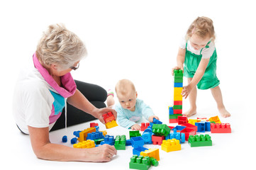 grandmother with grandchildren playing with blocks