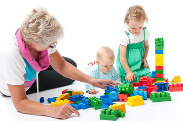 grandmother with grandchildren playing with blocks